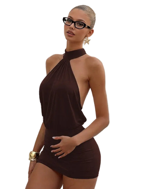 Woman wearing a brown halter neck dress standing against a white wall.