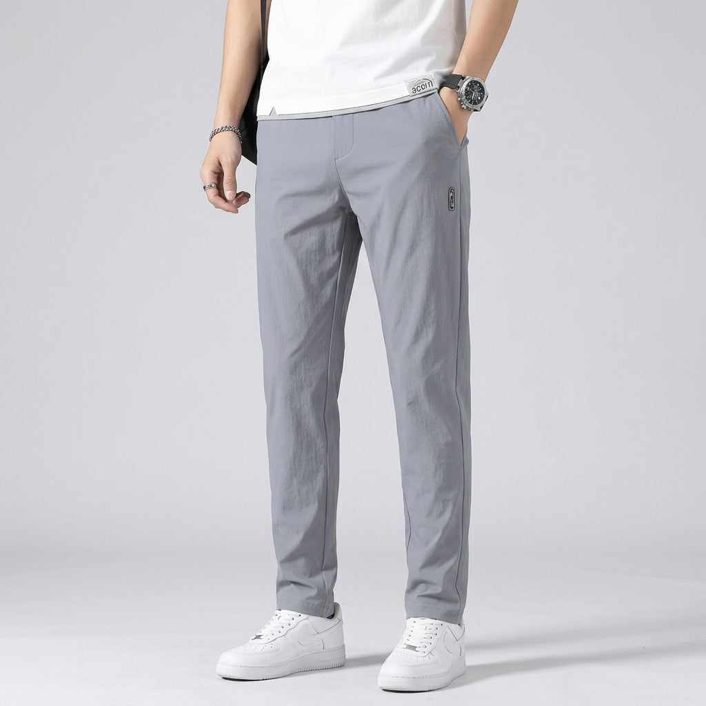 Person wearing gray pants and white sneakers on a gray background