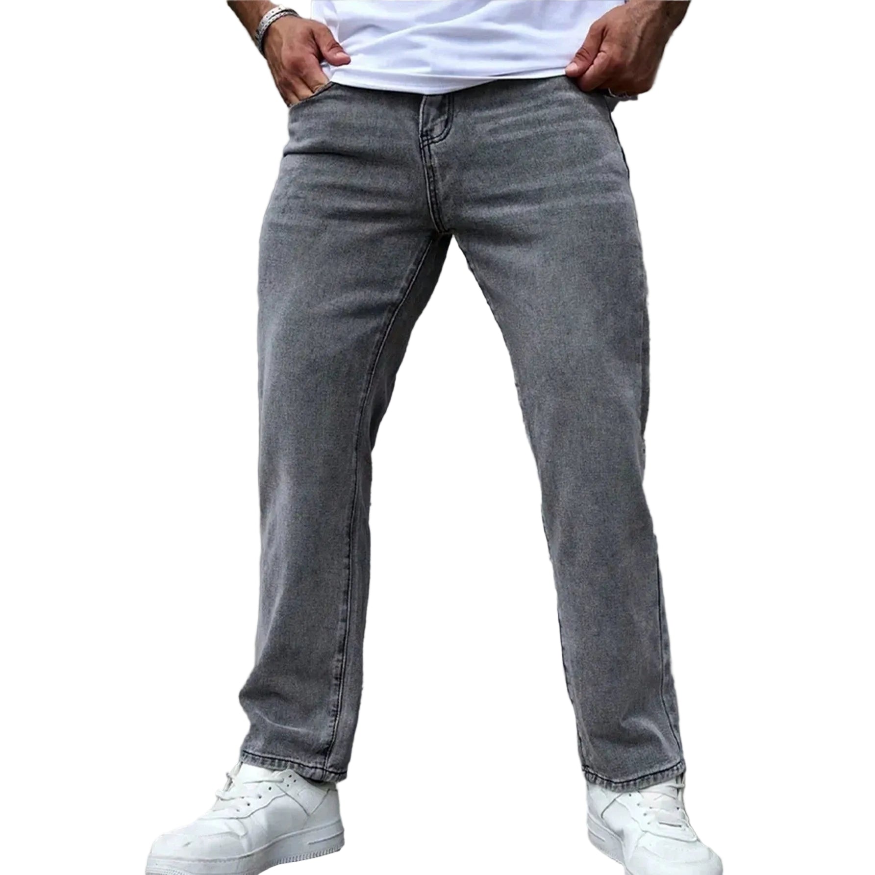 A person wearing gray washed denim jeans, a white t-shirt, and white sneakers, standing against a textured gray concrete wall.