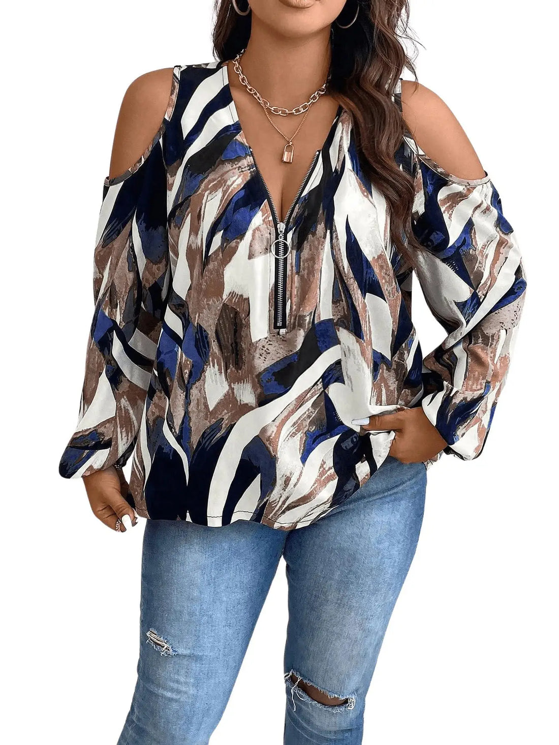 Woman wearing a patterned blouse with long sleeves and ripped jeans on a white background