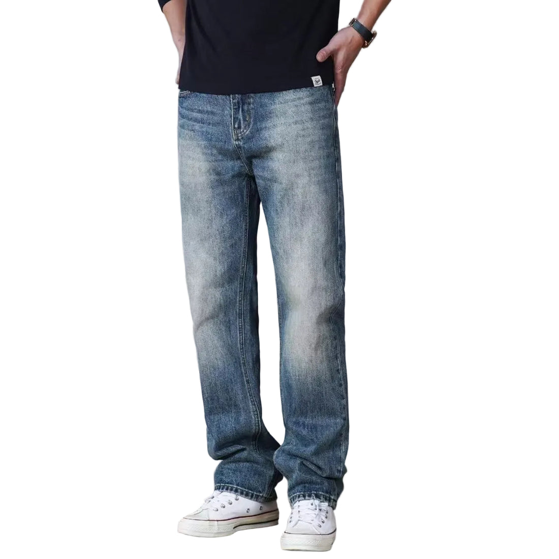 A man modeling a black short-sleeve crewneck t-shirt and light blue straight-leg jeans with white sneakers, standing against a solid light gray background.
