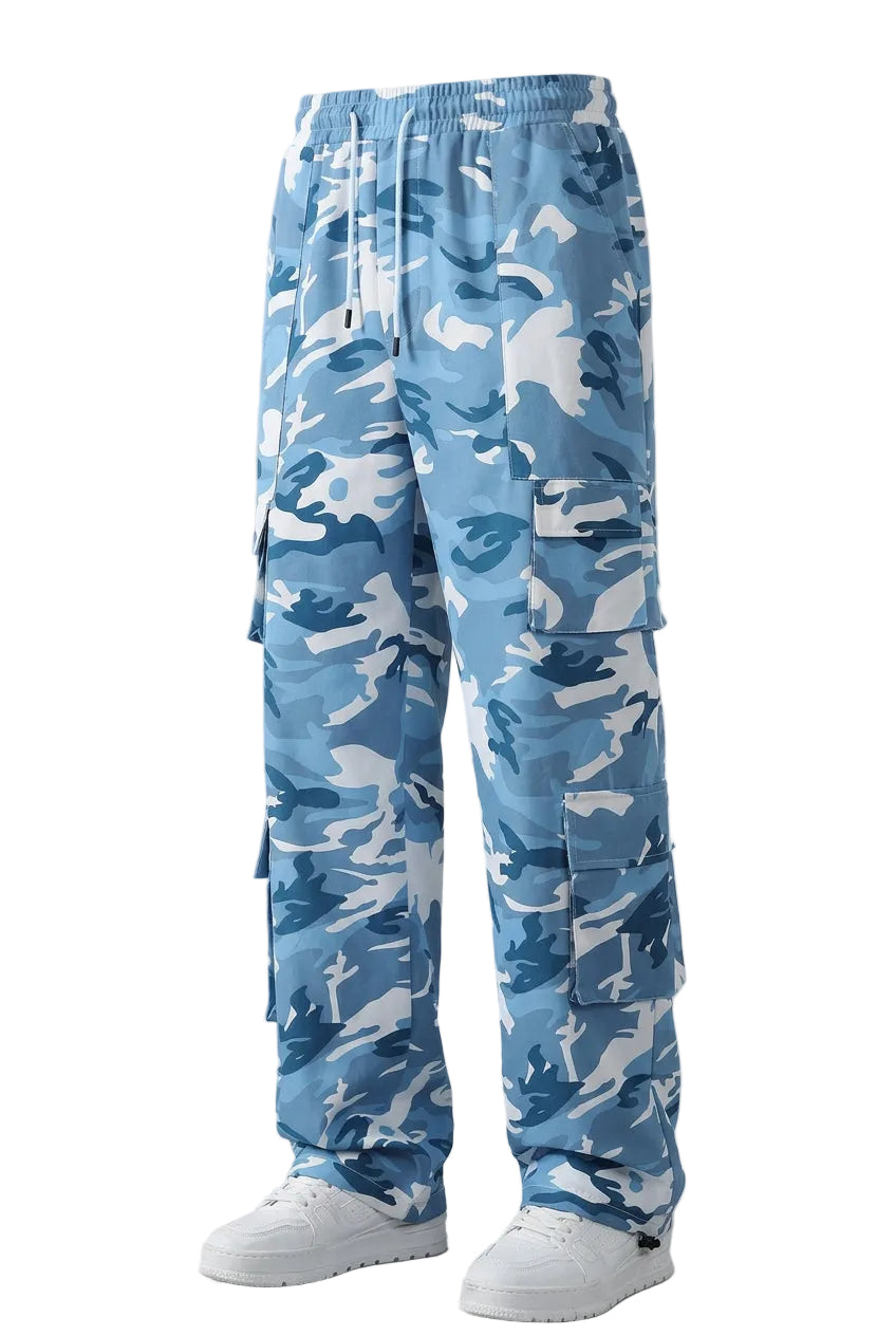 A person wearing blue camouflage cargo pants with a white sweatshirt and white sneakers, shown from the chest down against a light gray studio background. The image includes vertical text reading 'Camouflage mei shi' and 'Workwear,' plus two small inset photos showing additional camouflage colorways.