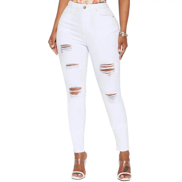 White distressed skinny jeans with ripped details on the thighs and knees, shown on a model wearing clear high-heeled sandals against a white background.