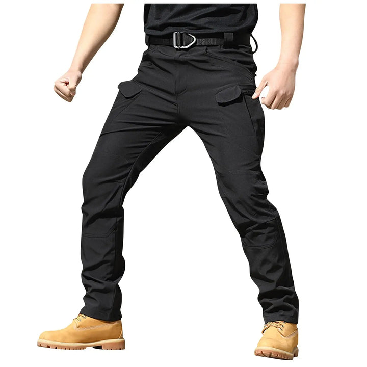 Person wearing black tactical pants with a belt and tan boots on a white background