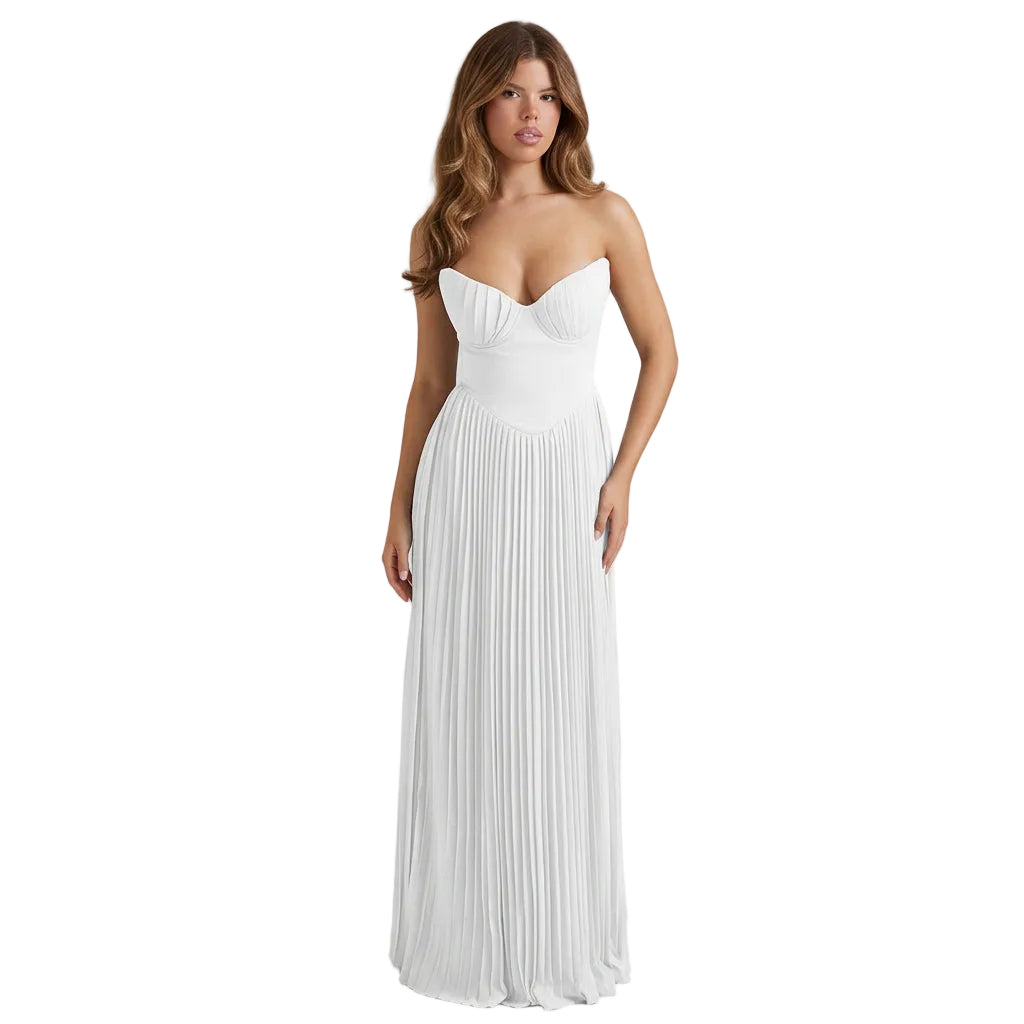 Woman in a white dress standing on a balcony with a scenic view of the ocean.