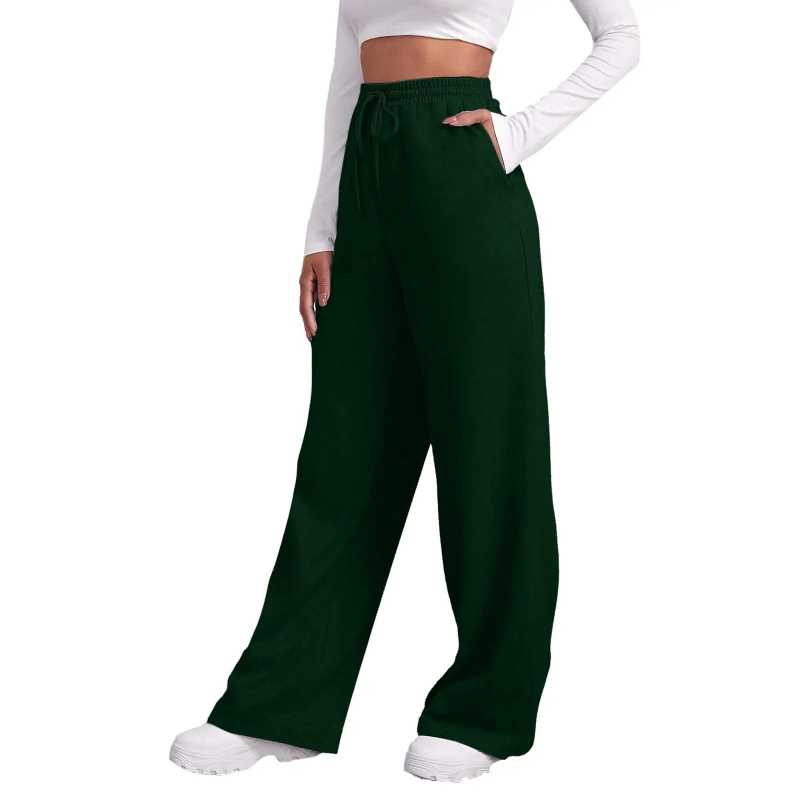 A person wearing dark forest green wide-leg drawstring pants with side pockets, styled with a white long-sleeve crop top and white sneakers against a plain white background.