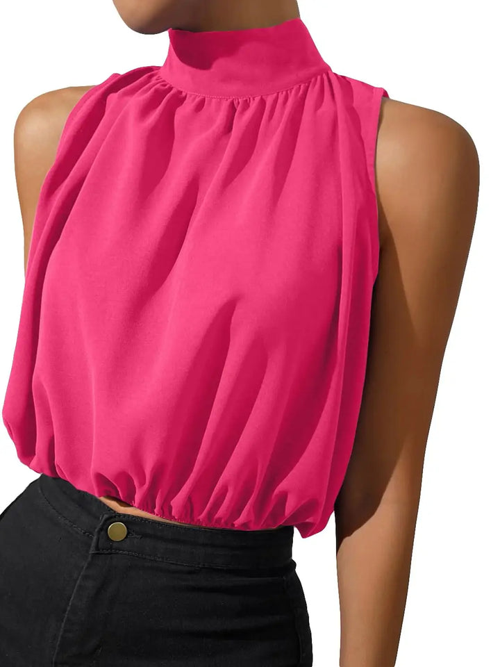 A sleeveless high-neck top in bright pink, shown on a model from the neck down wearing black pants against a white background.
