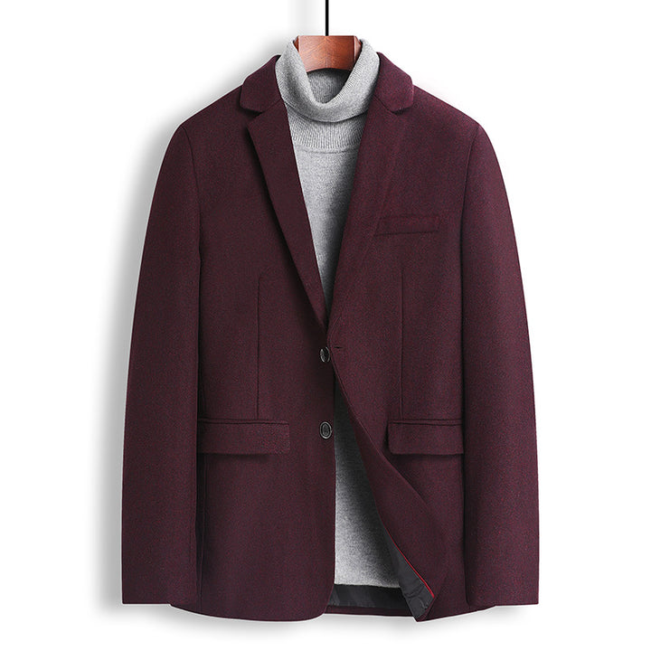 A men's blazer in deep burgundy, styled over a gray turtleneck sweater and hanging on a wooden hanger against a plain white background.
