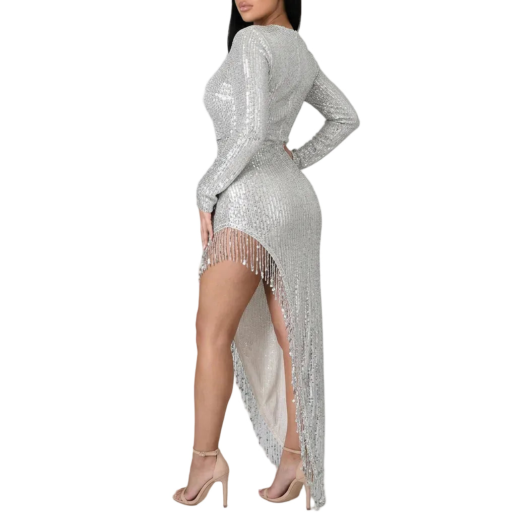A woman wearing a sparkling silver long-sleeve dress with a high-low fringe hem, standing in a living room setting.
