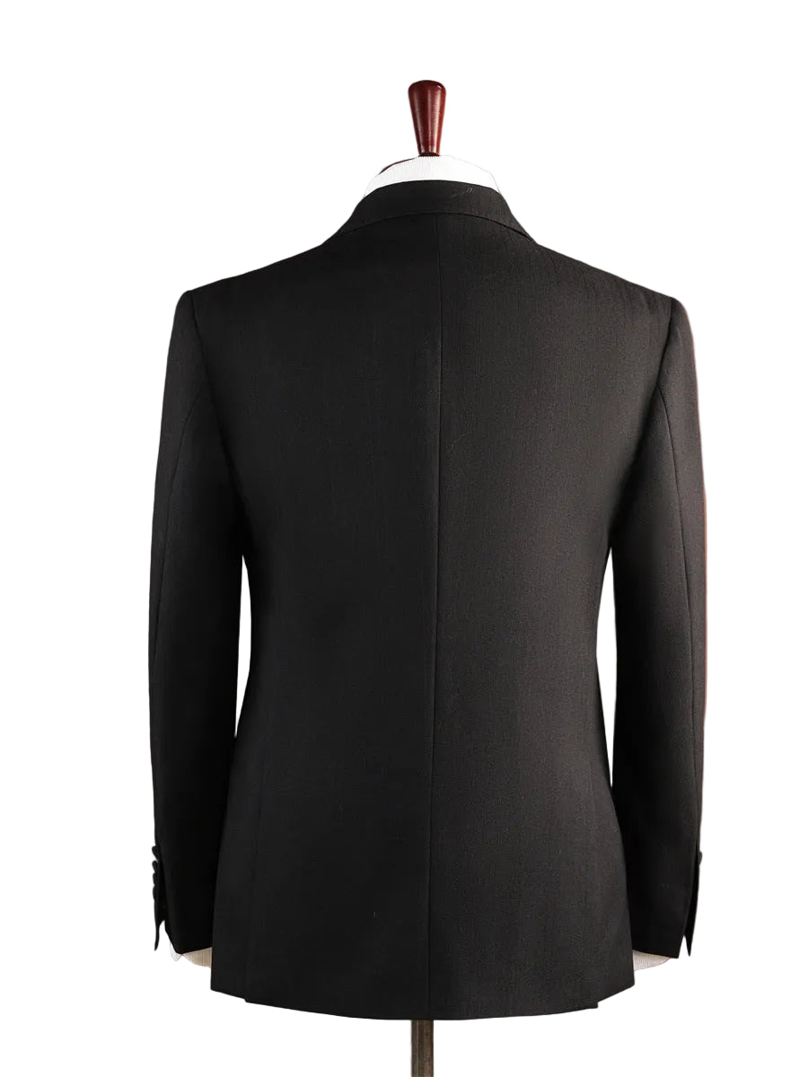 A black tailored suit jacket displayed on a mannequin from the back, set against a warm terracotta background.