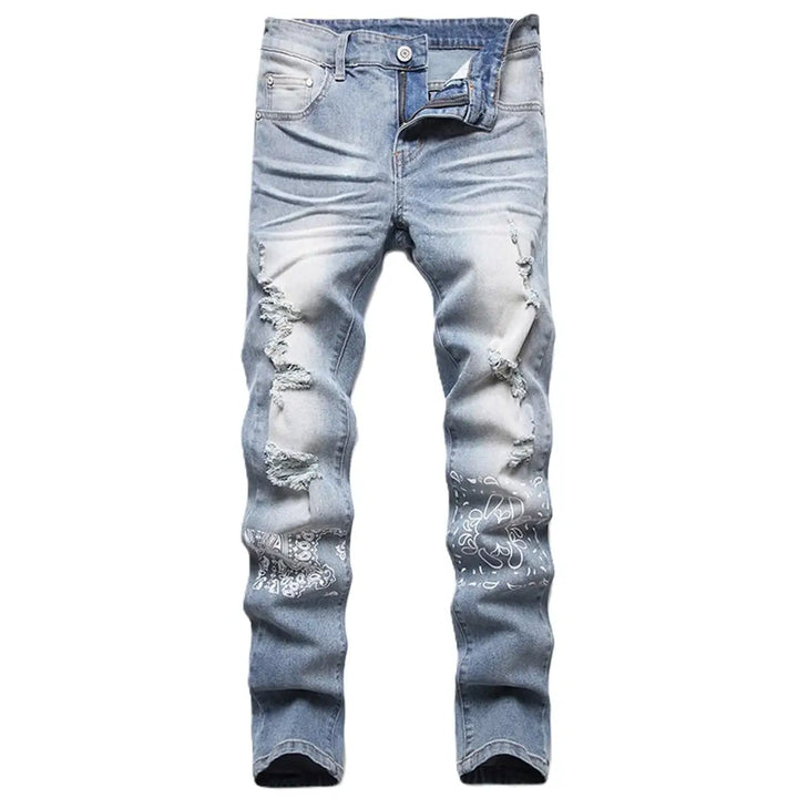 Ripped light blue jeans with floral embroidery on a white background