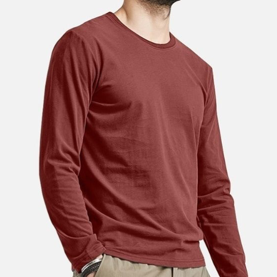 A man wearing a solid rust-red long-sleeve crewneck t-shirt, cropped from the chin down, against a light gray background.