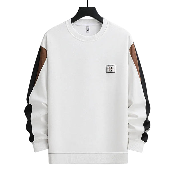 A white crewneck sweatshirt with brown and black color-blocked sleeves, featuring a small embroidered square patch with the letter 'R' on the left chest, displayed on a black hanger against a white background.