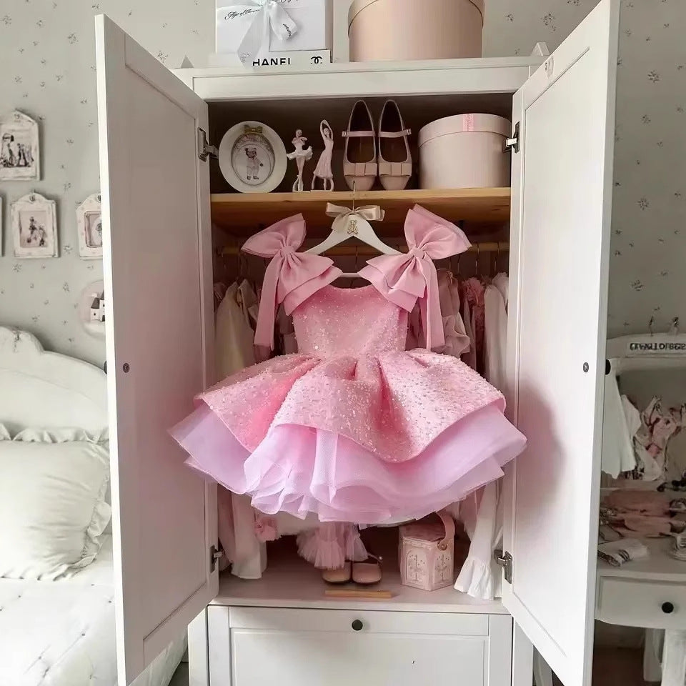 Pink dress with large bows displayed inside an open wardrobe.