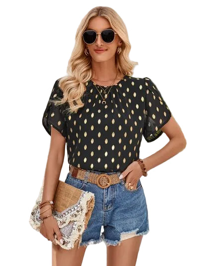Woman wearing a black polka dot top and denim shorts outdoors.