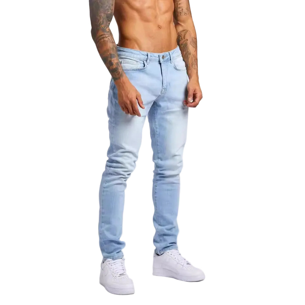 Person wearing light blue jeans and white sneakers on a plain background