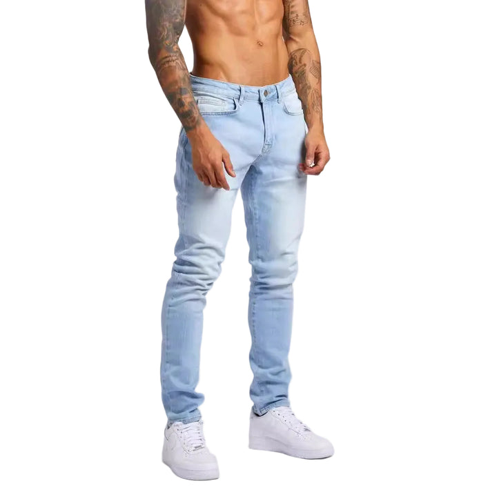 Person wearing light blue jeans and white sneakers on a plain background