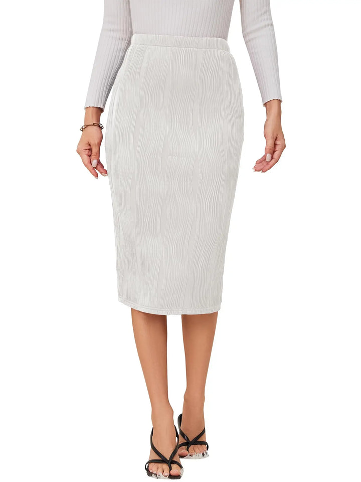 A woman wearing a light gray ribbed knit midi skirt with a textured vertical pleated pattern, paired with a matching ribbed long-sleeve top and black strappy heels, shown against a plain white background.