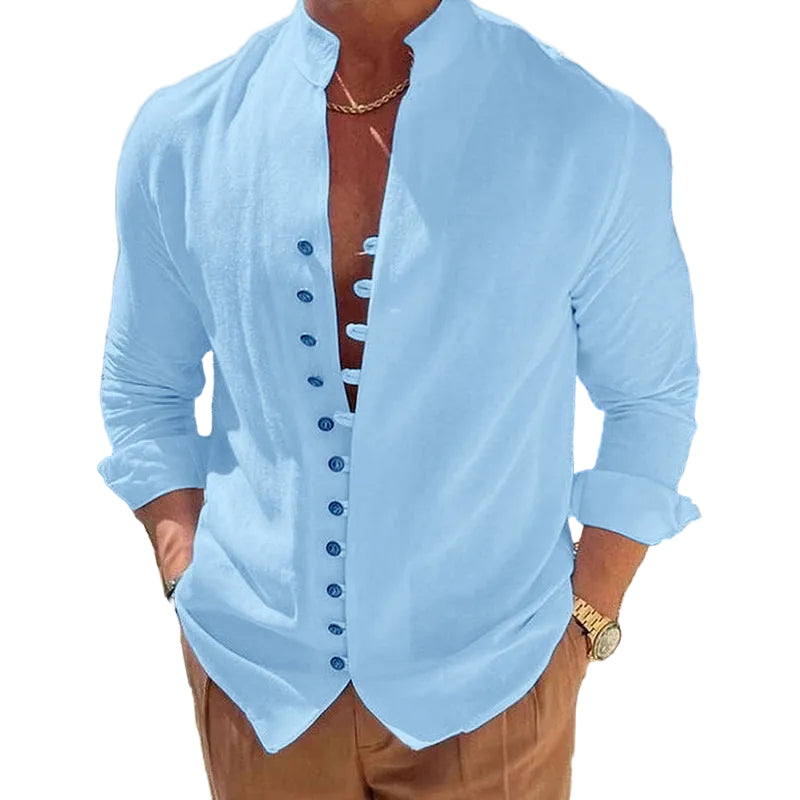 Man wearing a light blue button-up shirt with a blurred outdoor background