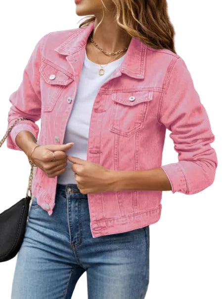 Person wearing a pink denim jacket over a white shirt and blue jeans, standing against a beige wall.