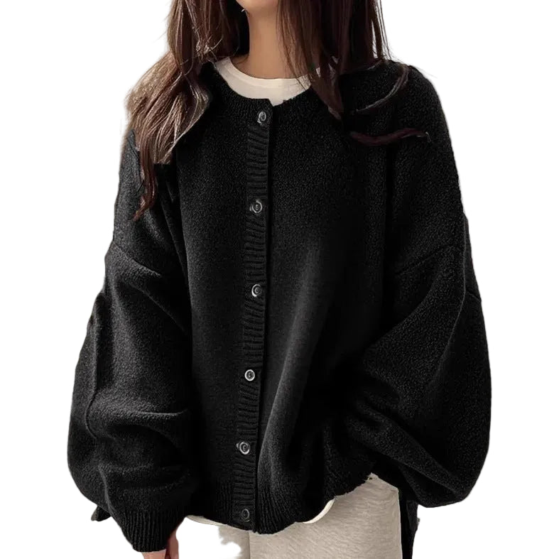 Person wearing a black cardigan over a white shirt on a beige background