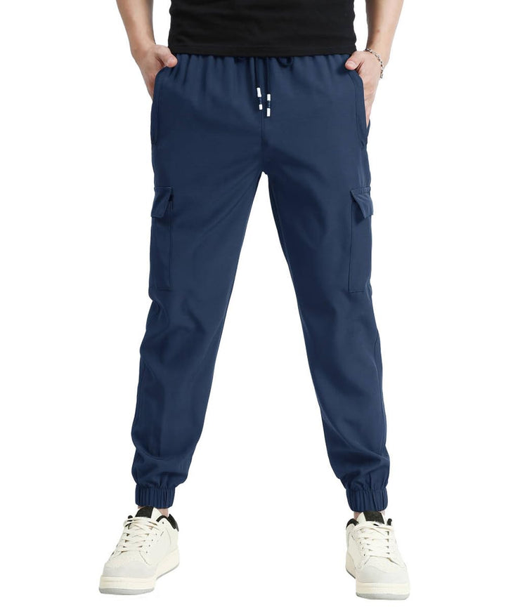 A person wearing navy blue cargo jogger pants with side cargo pockets, elastic cuffs, and a drawstring waist, paired with white sneakers against a plain white background.