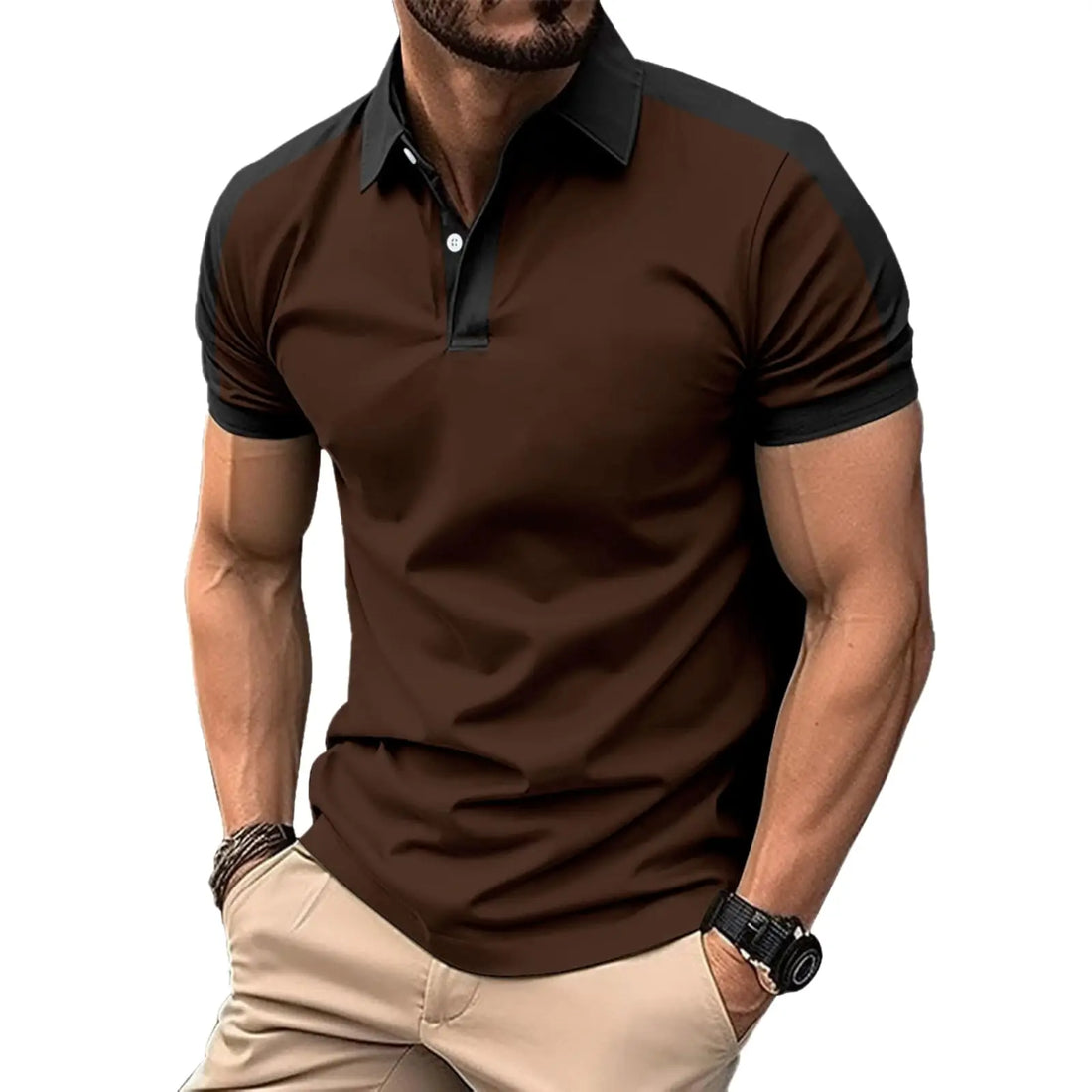 A man wearing a short-sleeve polo shirt with a dark brown body and black collar and shoulder panels, paired with beige pants, against a plain white background.