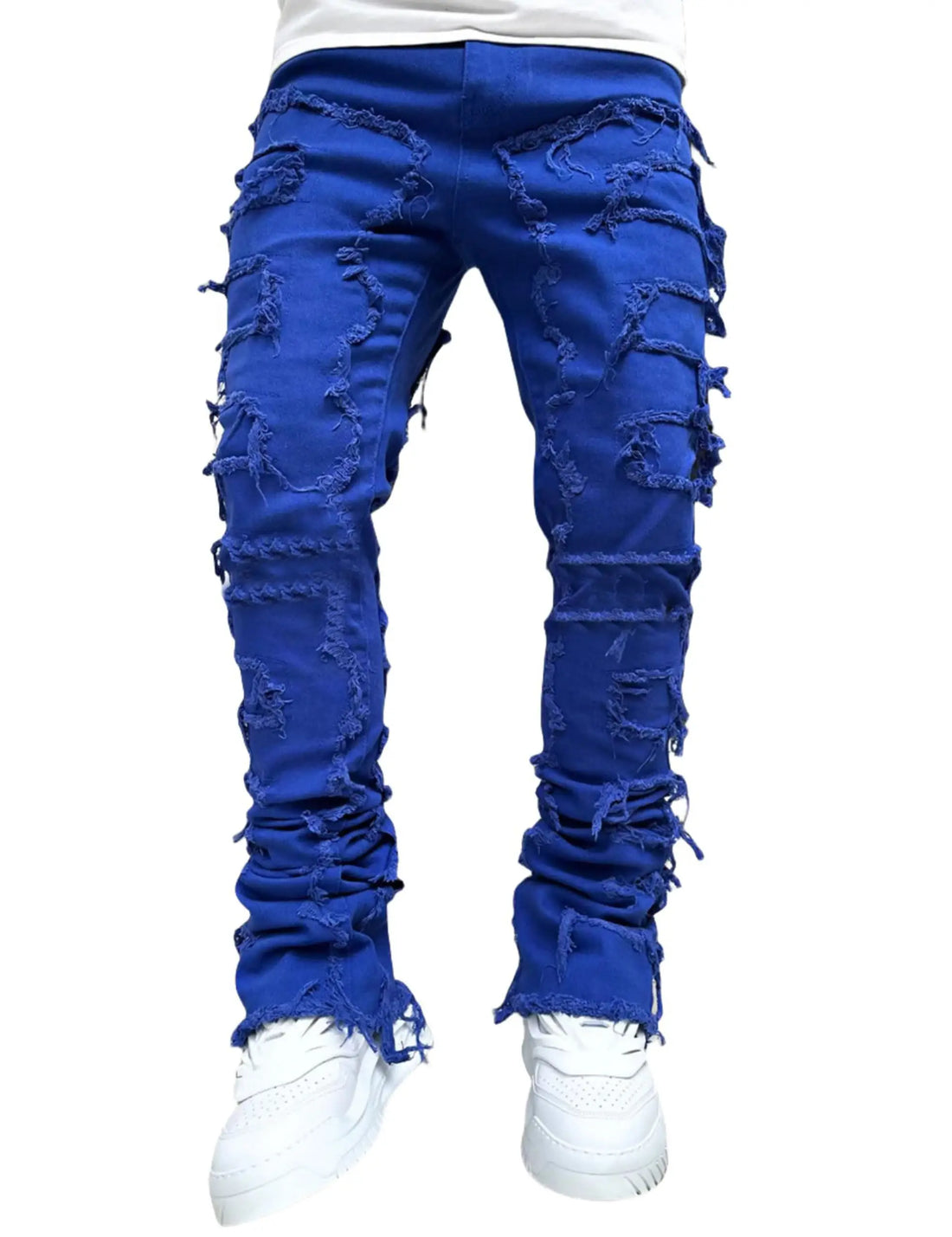 Blue distressed jeans worn with white sneakers on a white background