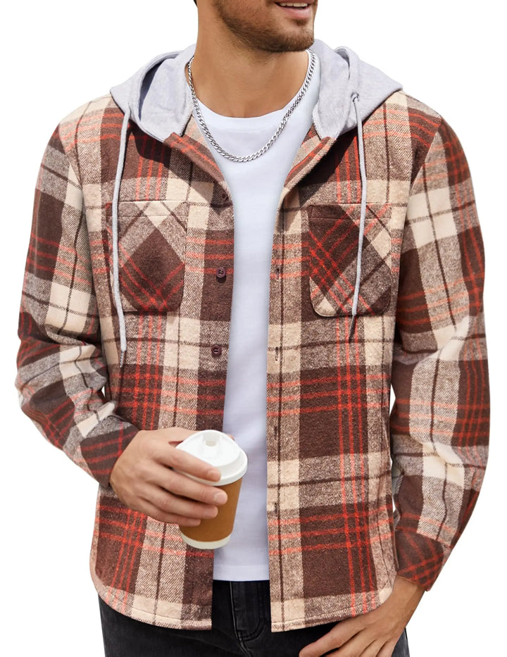 A man wearing a brown, beige, and red plaid hooded flannel shirt over a white t-shirt, holding a coffee cup against a plain white background.