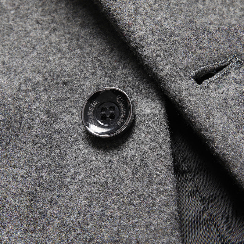 Close-up of a gray wool-blend coat with a dark metal button and folded lapel showing a black inner lining.