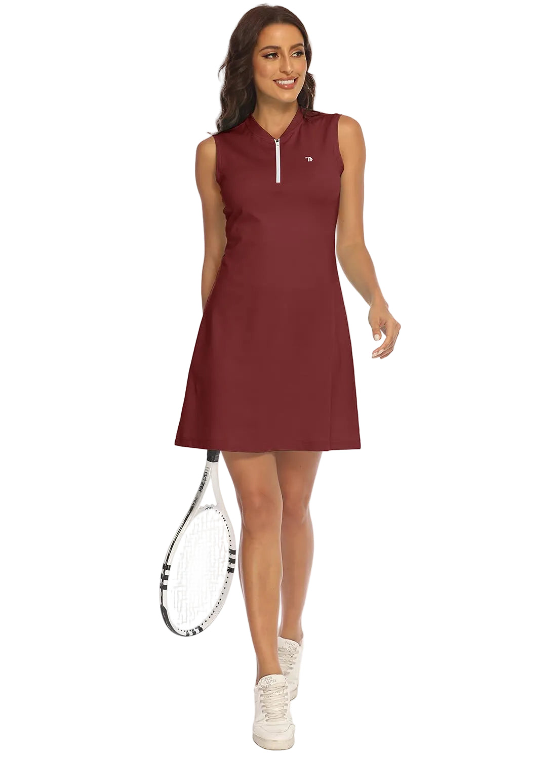 A woman modeling a sleeveless, knee-length athletic dress in burgundy with a half-zip neckline. She is holding a tennis racket and wearing white sneakers against a plain white background.