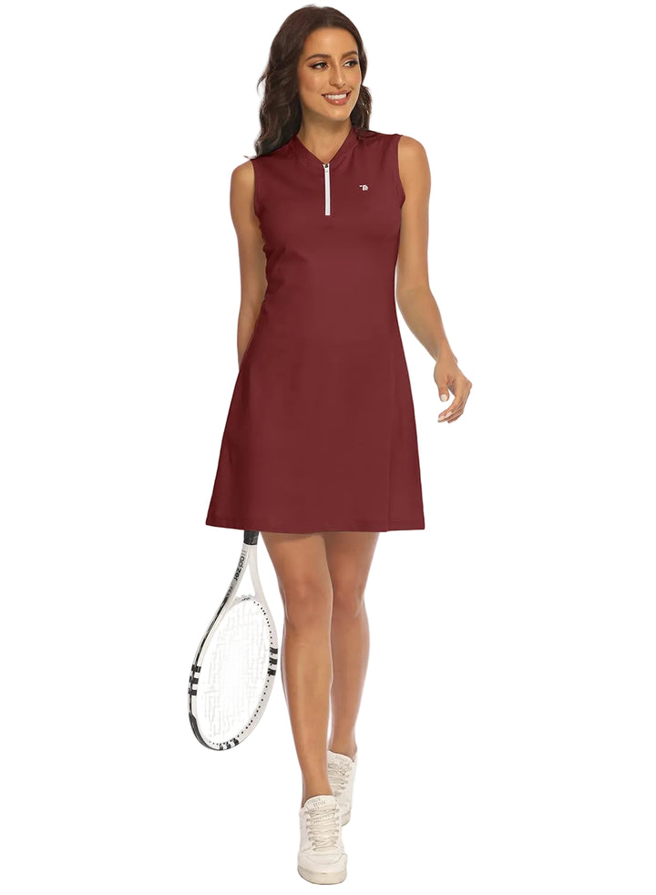 A woman modeling a sleeveless, knee-length athletic dress in burgundy with a half-zip neckline. She is holding a tennis racket and wearing white sneakers against a plain white background.