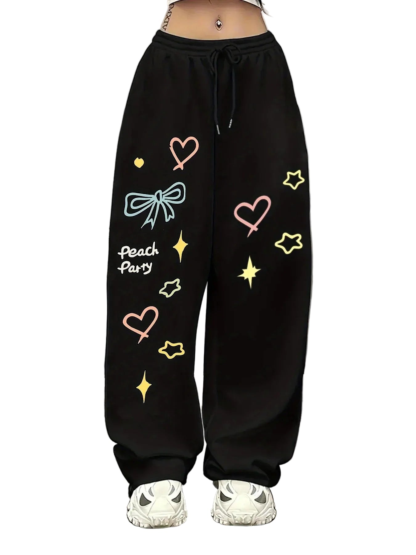 Black wide-leg sweatpants with colorful graphic prints including hearts, bows, stars, sparkles, and the text 'Peach Party', shown on a model from the waist down wearing white sneakers.