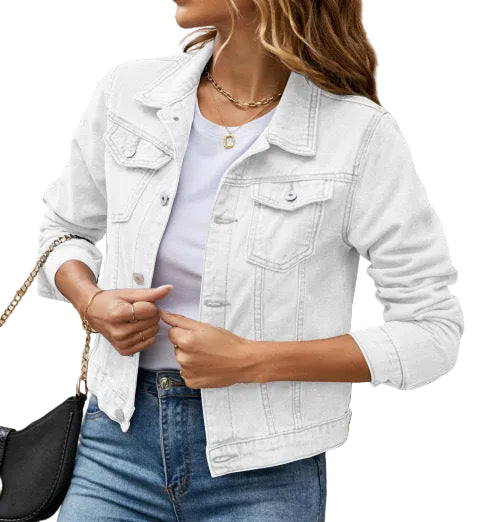 Person wearing a white denim jacket over a light blue shirt, standing against a beige wall.