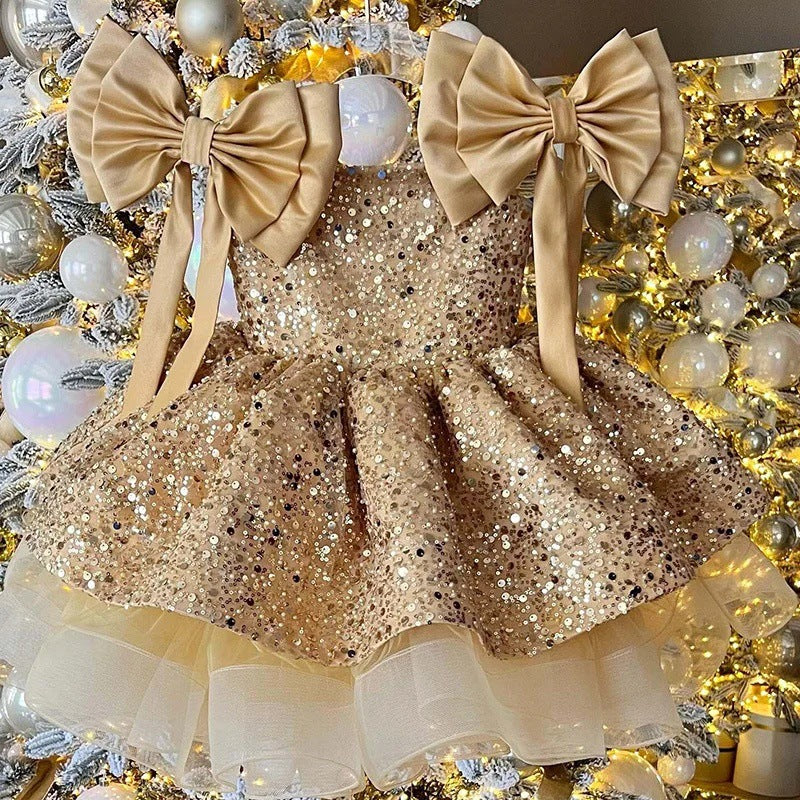 Gold sequin dress with large bows on a decorative background