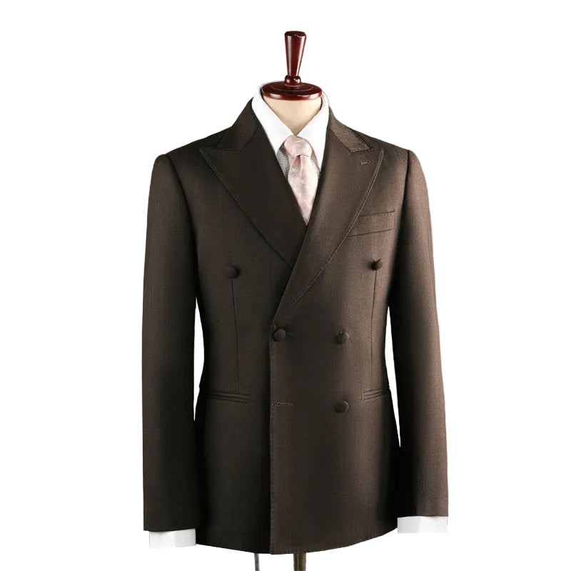 A dark brown double-breasted suit jacket displayed on a mannequin torso with a white dress shirt and light pink tie, set against a warm terracotta background.