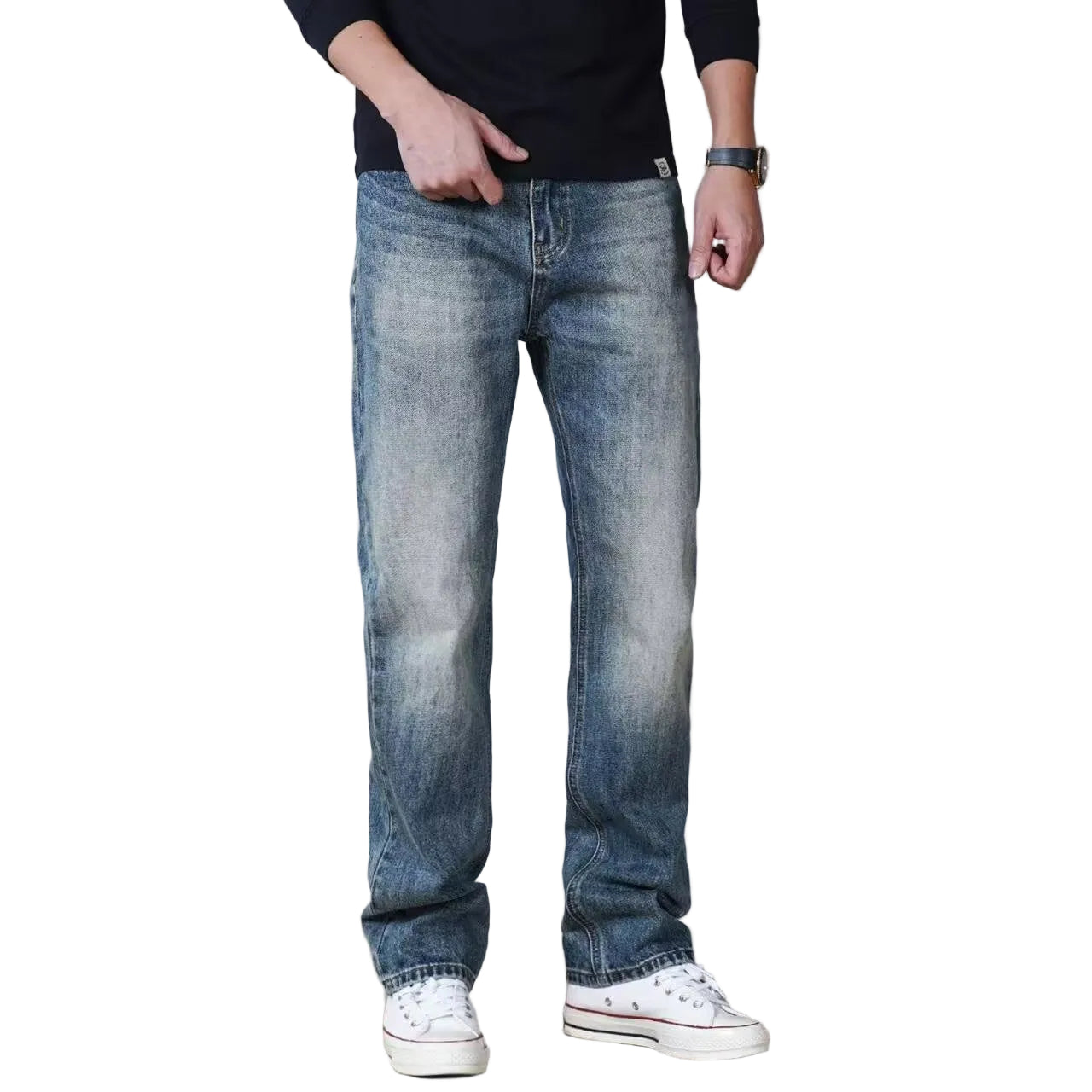 A person wearing medium-wash blue straight-leg denim jeans with a faded wash, paired with a black long-sleeve shirt and white low-top sneakers, shown from the waist down against a light gray studio background.