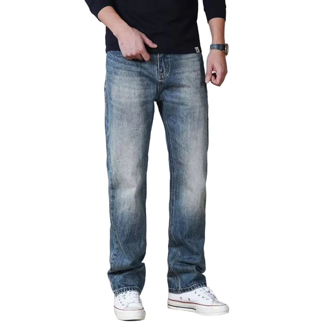 A person wearing medium-wash blue straight-leg denim jeans with a faded wash, paired with a black long-sleeve shirt and white low-top sneakers, shown from the waist down against a light gray studio background.