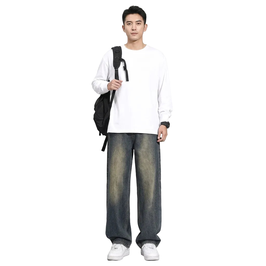 A person wearing loose, wide-leg faded blue jeans with a white shirt, white sneakers, and a black backpack, shown from the waist down on a plain white background.