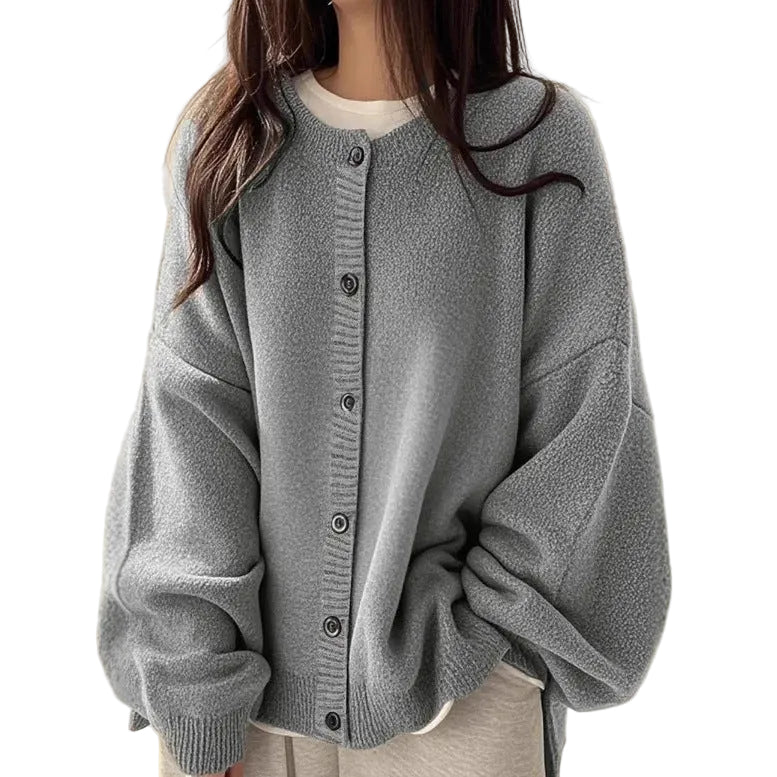 A woman wearing an oversized light gray knit cardigan with a button front, shown from the neck down against a plain beige background.