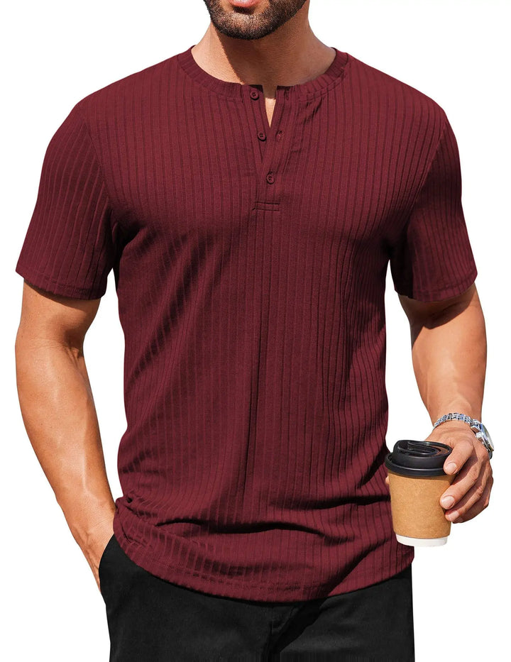 Man wearing a maroon ribbed henley shirt holding a coffee cup on a white background