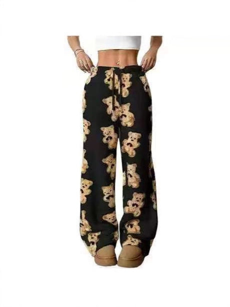 Black wide-leg sweatpants with an all-over teddy bear print, modeled from the waist down on a white background.