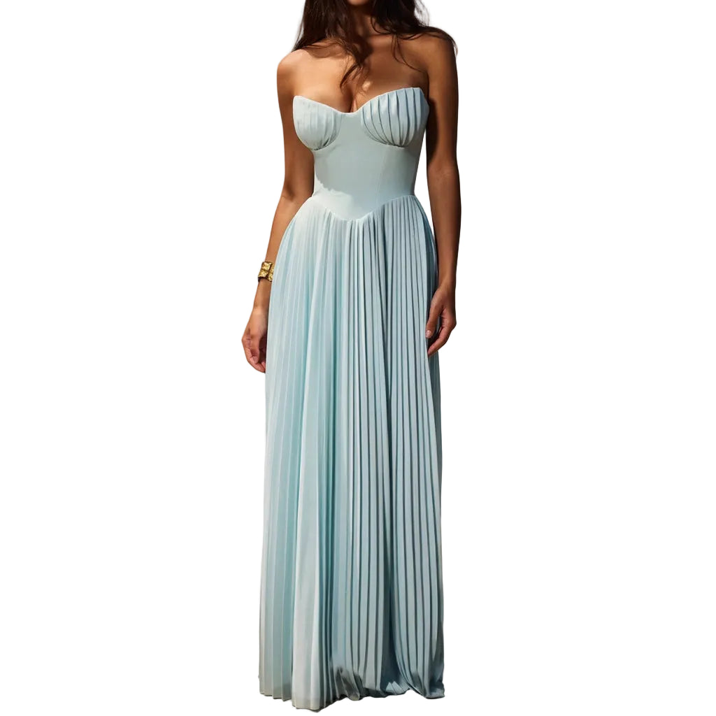 Woman in a light blue dress standing on a beach with ocean waves in the background