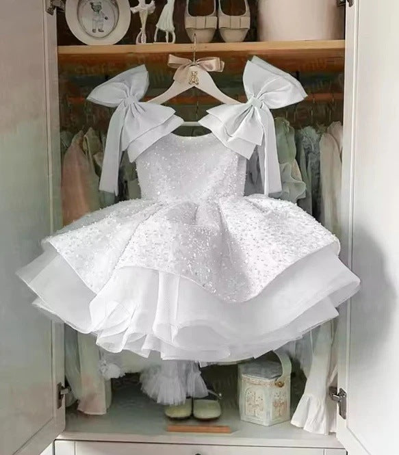White sequin dress with large bows on hangers inside a wardrobe.