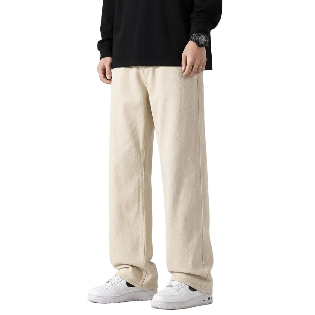 A person wearing light-wash wide-leg jeans, a black long-sleeve shirt, and white sneakers, standing against a plain gray studio background.