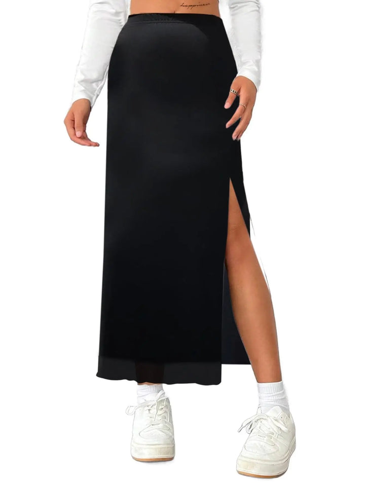 Person wearing a black maxi skirt with a white top and sneakers on a white background