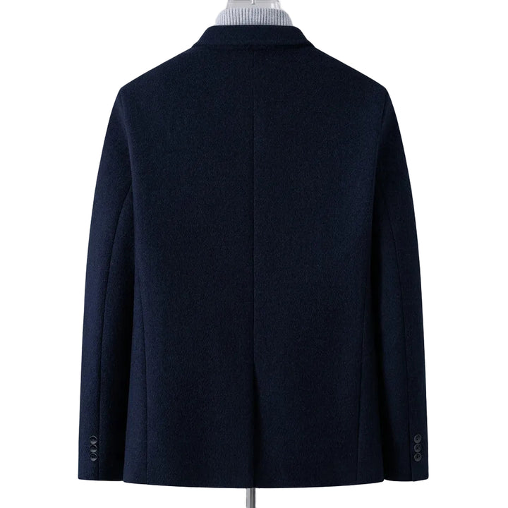 A dark navy blue men's coat shown from the back, displayed on a mannequin torso with a striped shirt collar visible at the neck. A flame graphic with the text 'Fleece-lined' appears in the lower right corner to indicate the lining feature.