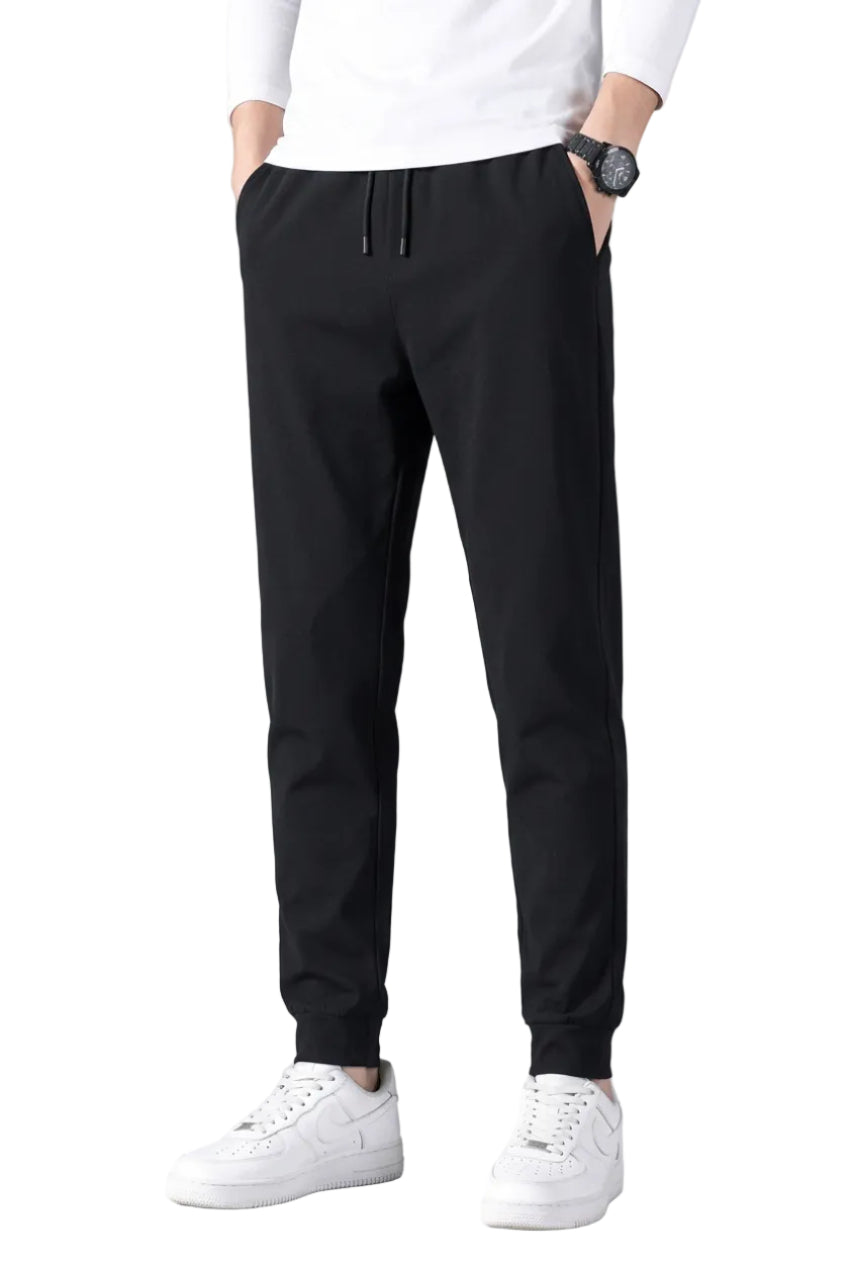 Person wearing black pants and white sneakers on a gray background
