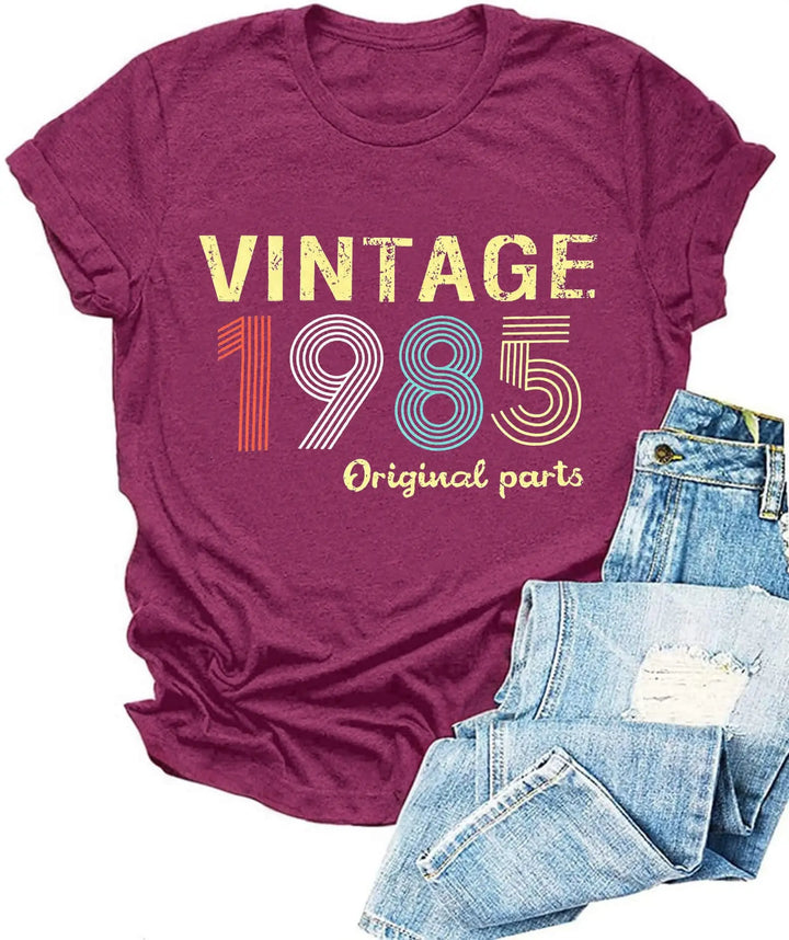 Maroon t-shirt with 'Vintage 1985 Original parts' text and blue jeans on a white background