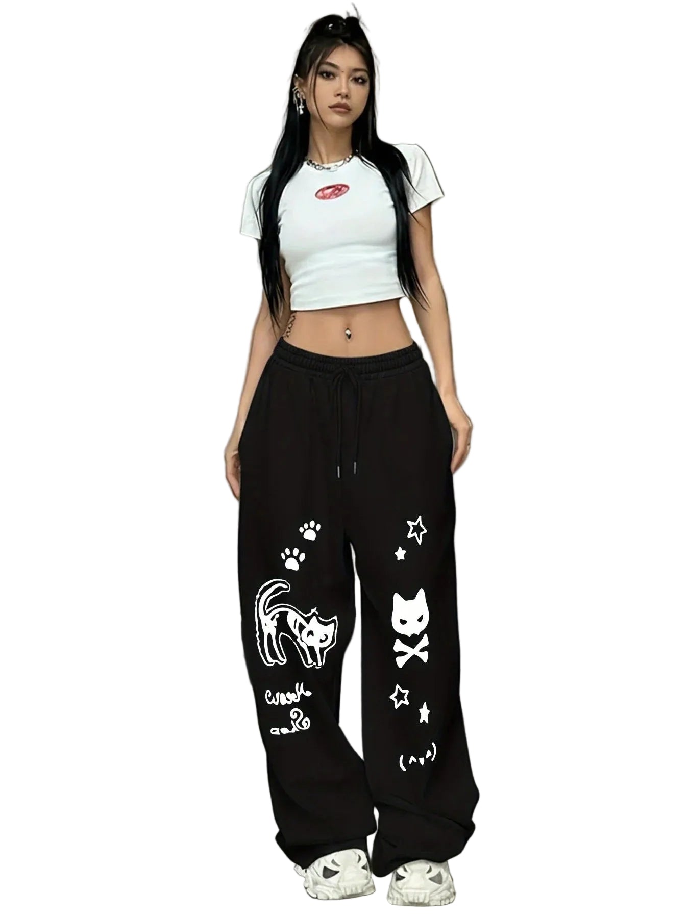 A woman modeling black sweatpants with white cat graphics, a white crop top, and white sneakers against a plain white background.